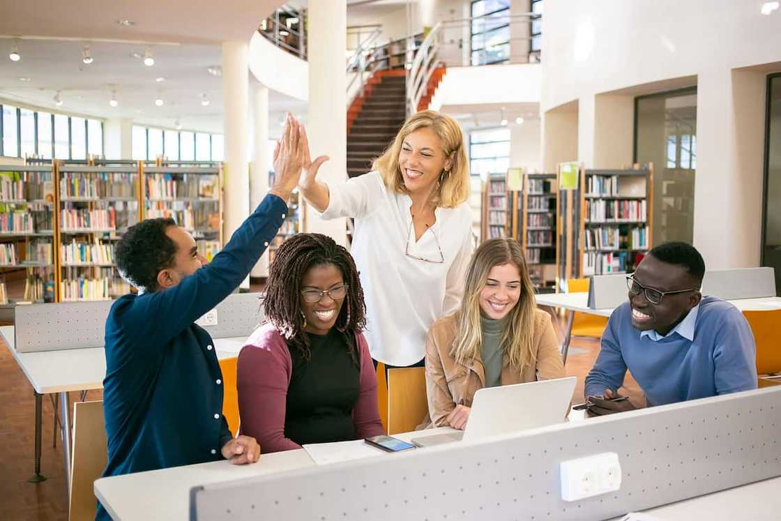 Cheerful students having a high-five with a teacher