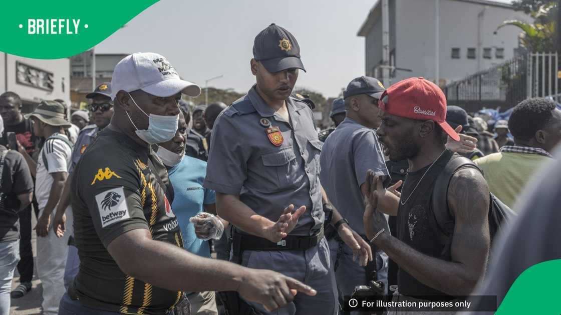 A South African Police Service (SAPS) officer stands between members of March and March Movement (L) and a foreign national during a demonstration against undocumented migrants in Durban, on September 3, 2026