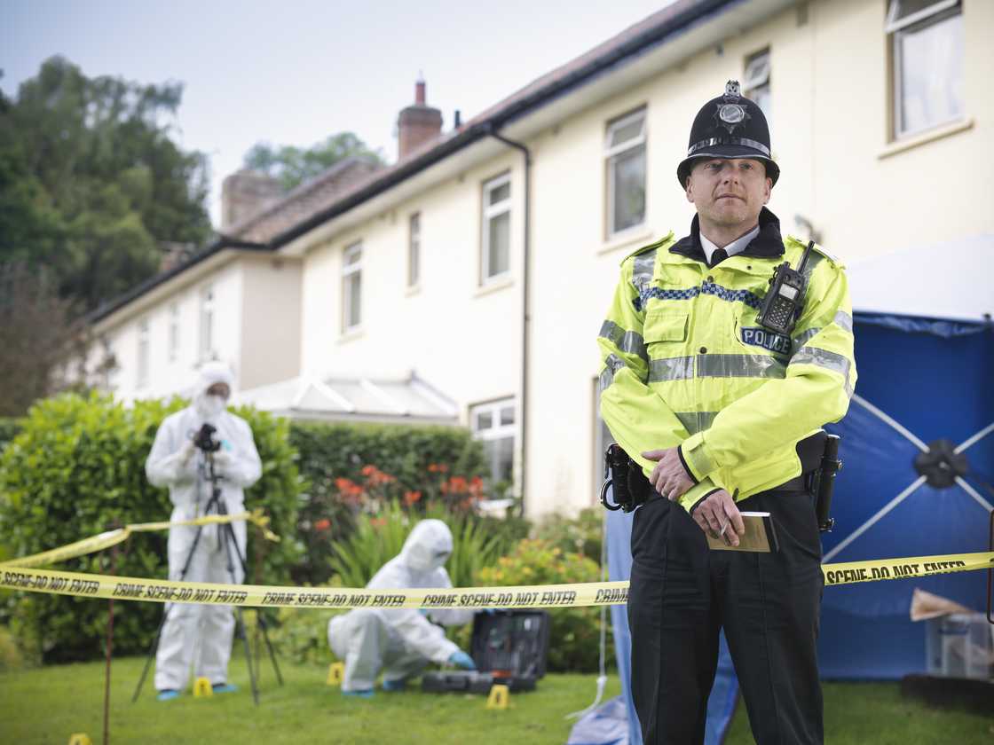 A policeman and forensic review officers A policeman and forensic review officers