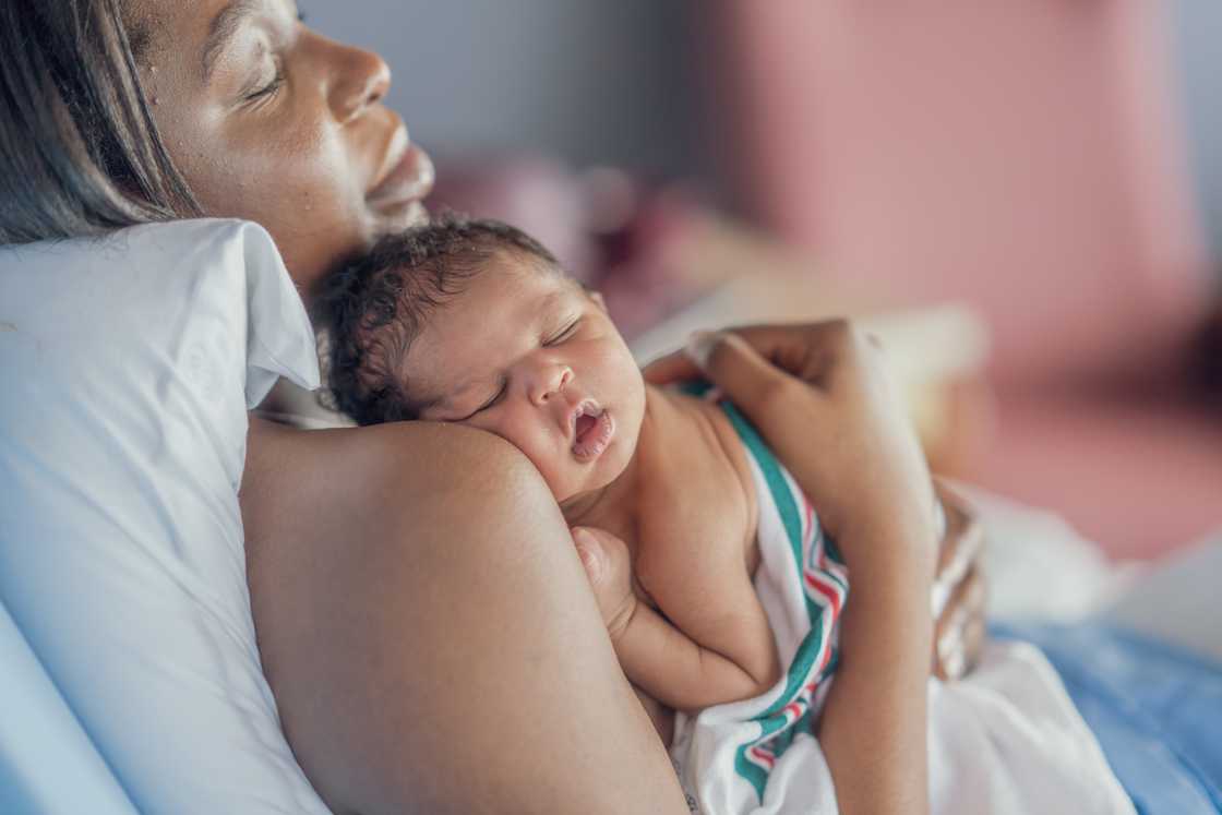 A woman holds her newborn baby on her chest. A woman holds her newborn baby on her chest.