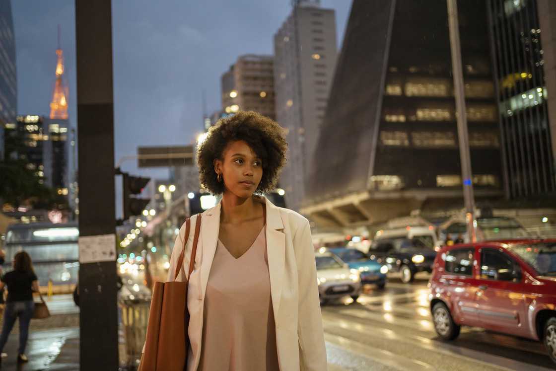 A woman walking calmly under the streetlights.