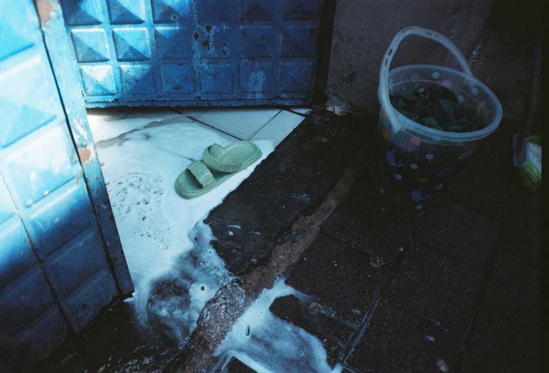 Water floods a tiled floor near a doorway and bucket.