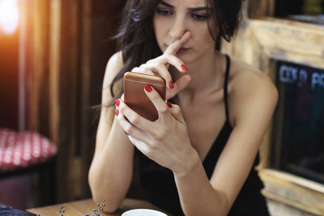 An upset woman looking at her phone.