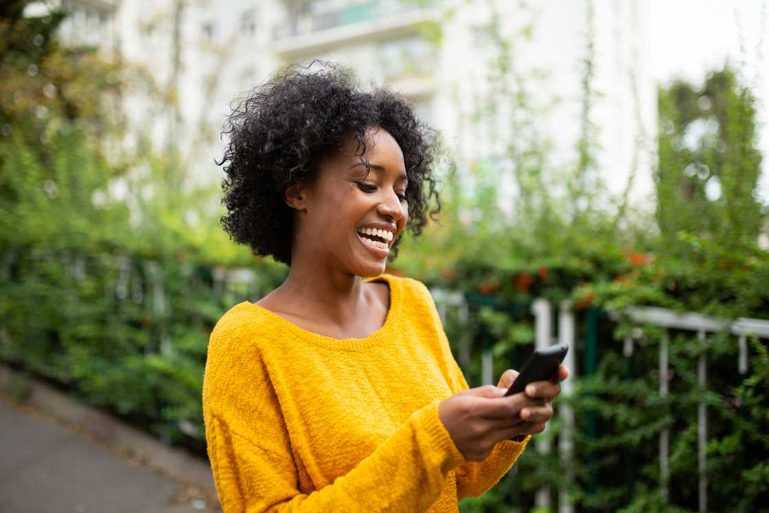 A woman smiling at her phone.