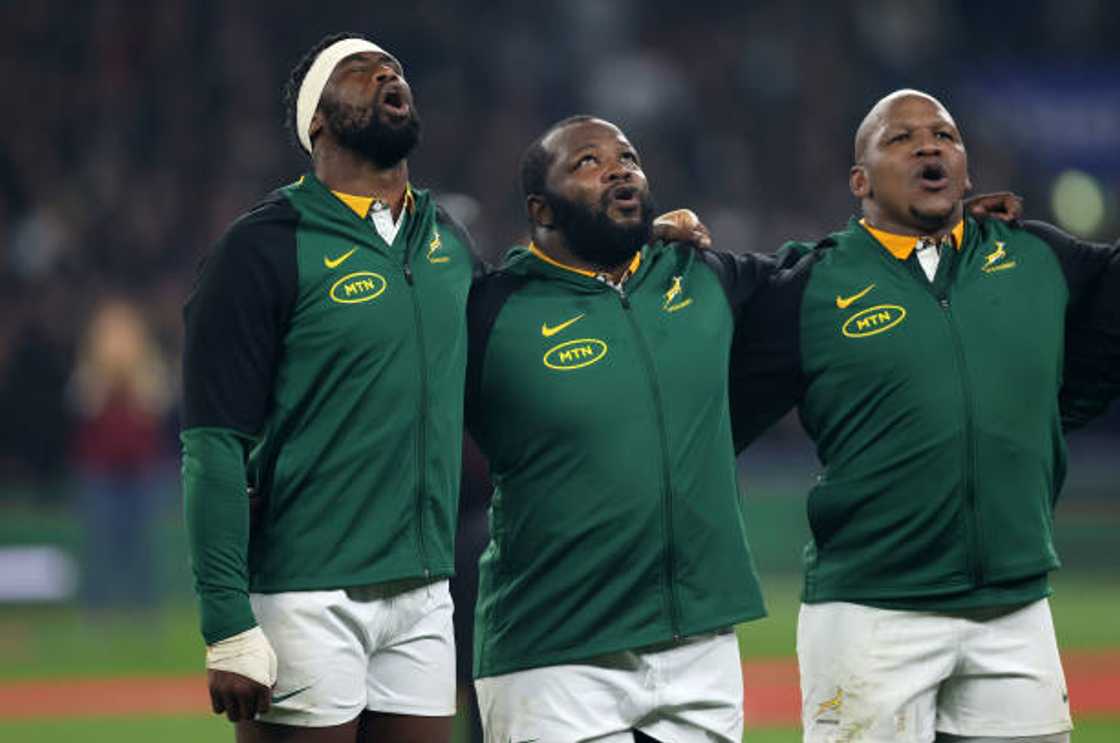 Siya Kolisi, Ox Nche, and Bongi Mbonambi singing the South African national anthem, showcasing team unity and solidarity.