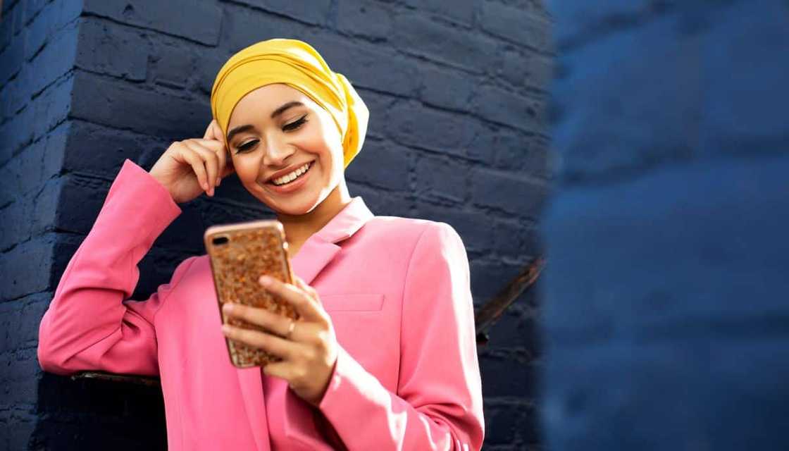 A woman looks at her phone while browsing online courses on GetSmarter