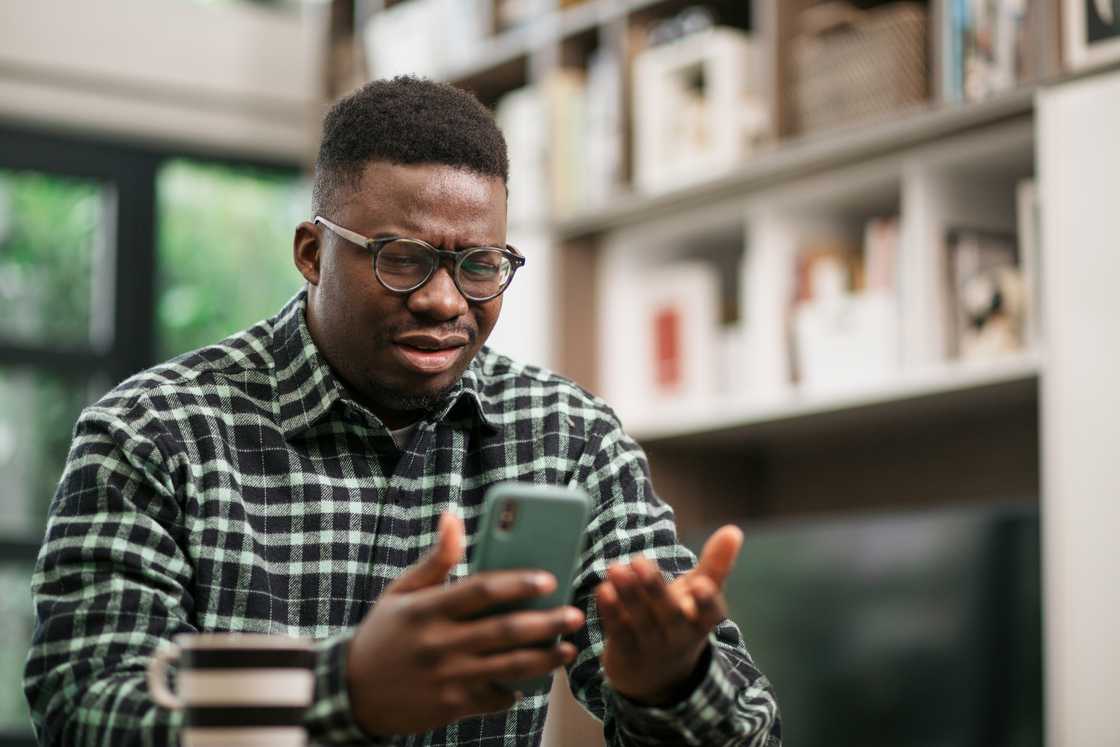 A confused man looking at his phone.