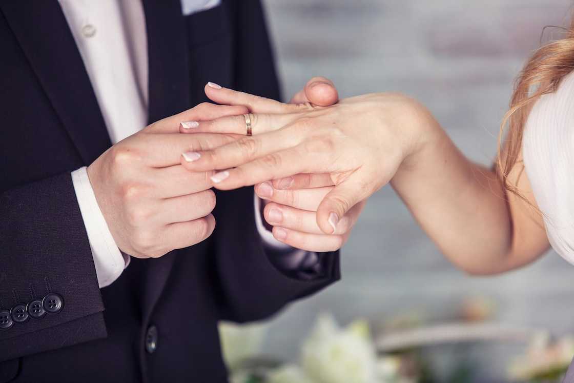 A groom putting a ring on the ring finger of the bride on the day of the wedding ceremony. A groom putting a ring on the ring finger of the bride on the day of the wedding ceremony.