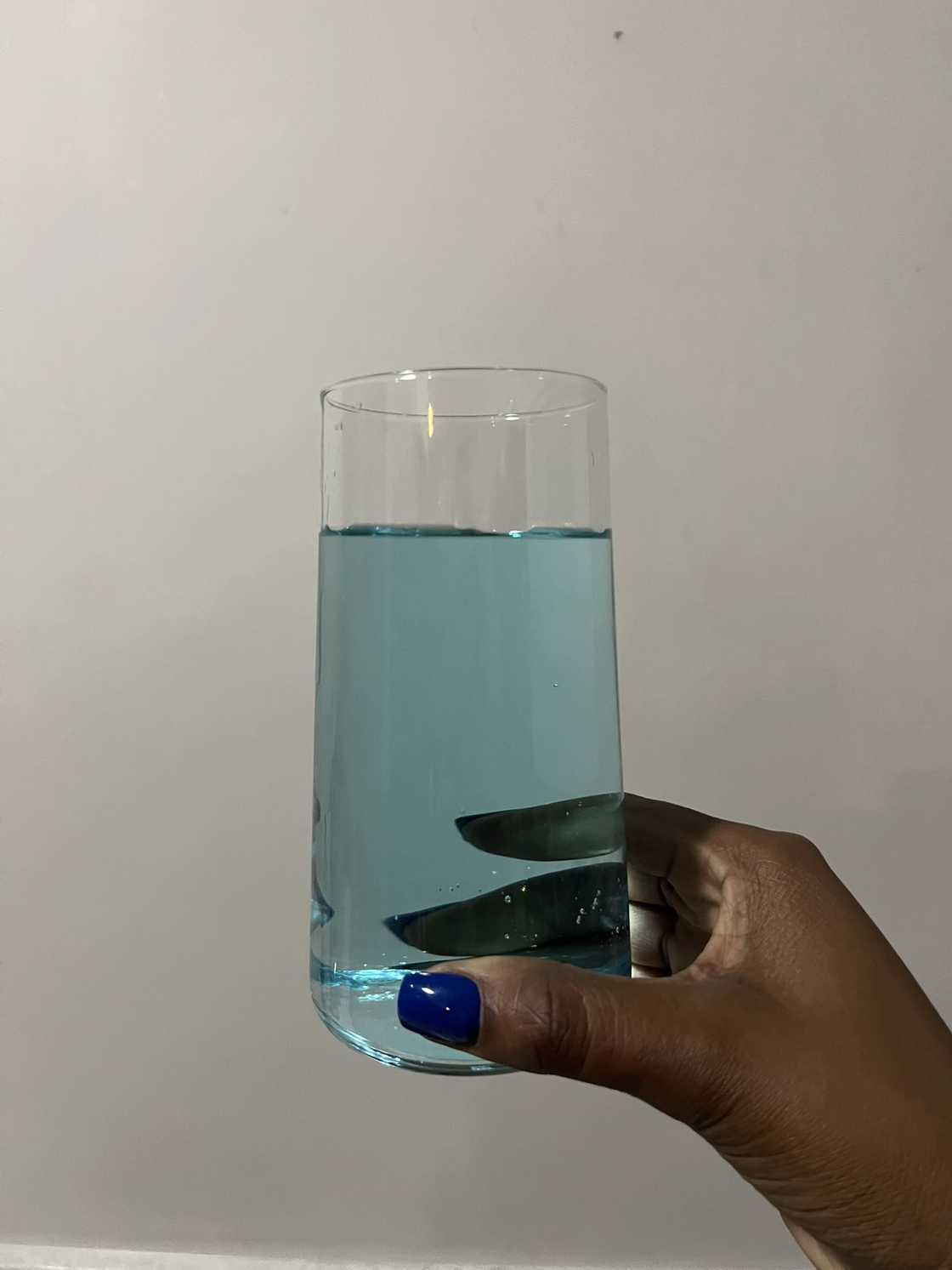 A woman showed her glass of blue water. A woman showed her glass of blue water.
