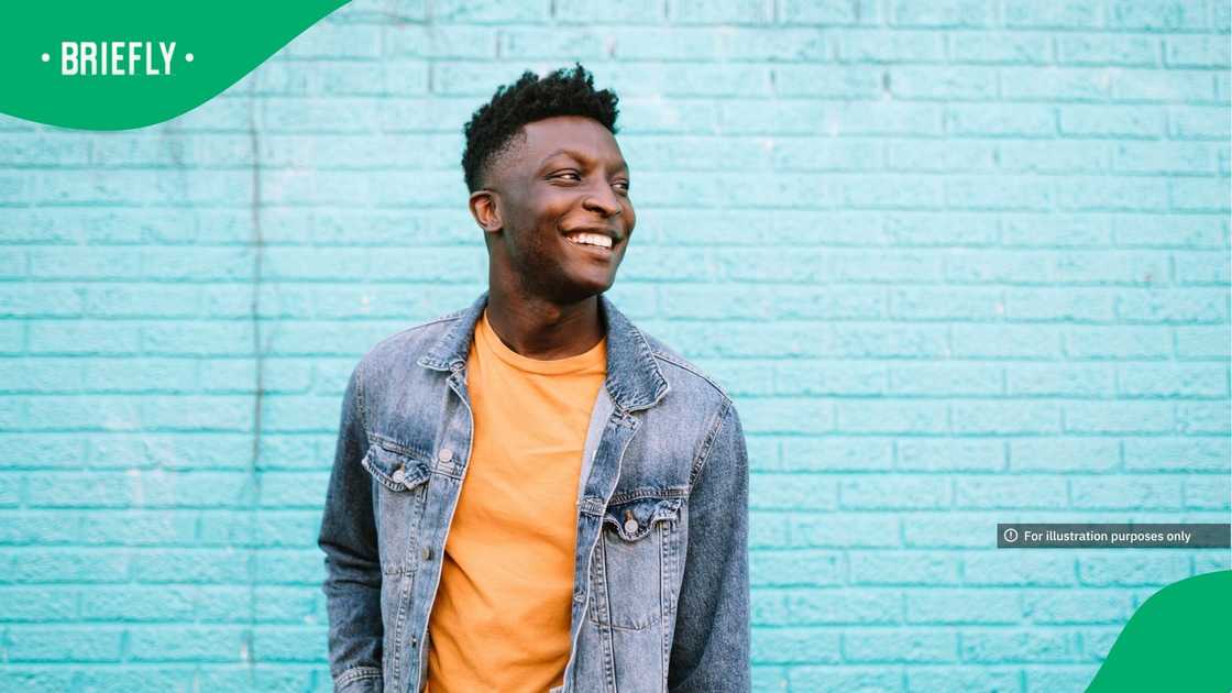 A smiling young man standing in front of a blue wall wearing nice casual clothing A smiling young man standing in front of a blue wall wearing nice casual clothing