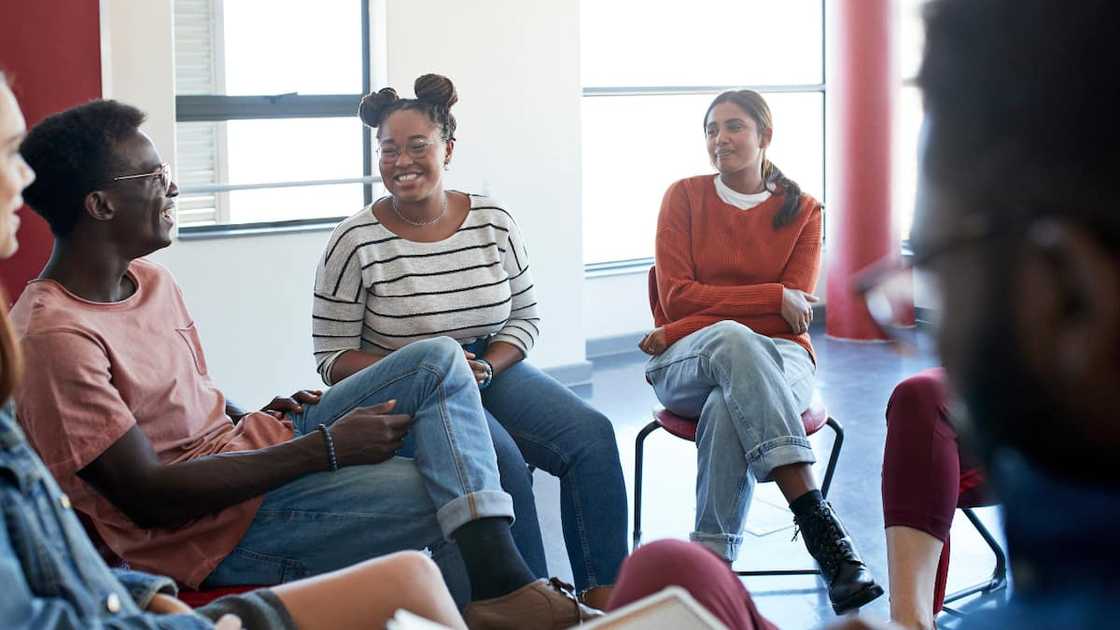 Smiling young university students sitting with instructor in classroom during psychotherapy Smiling young university students sitting with instructor in classroom during psychotherapy
