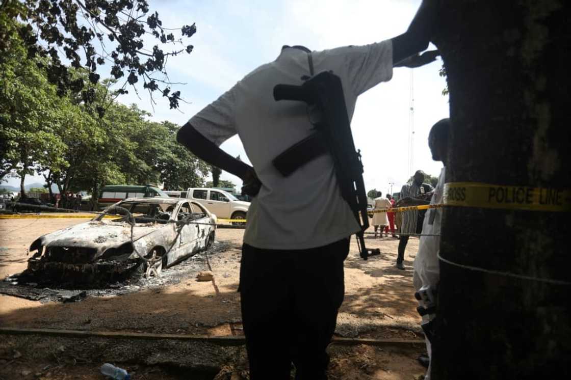A police officer stands beside a burnt prison vehicle in Abuja, Nigeria on July 6, 2022 after suspected Boko Haram gunmen attacked the Kuje Medium prison A police officer stands beside a burnt prison vehicle in Abuja, Nigeria on July 6, 2022 after suspected Boko Haram gunmen attacked the Kuje Medium prison