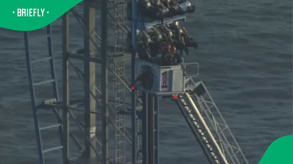 A firefighter stood inside the elevated bucket of a cherry picker crane, which had been raised high above the ground to reach the stuck passengers right at the edge of a steep drop A firefighter stood inside the elevated bucket of a cherry picker crane, which had been raised high above the ground to reach the stuck passengers right at the edge of a steep drop