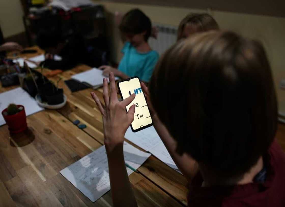 Velimir studies letters on a phone as he sits with other young Russian expats learning Serbian Velimir studies letters on a phone as he sits with other young Russian expats learning Serbian