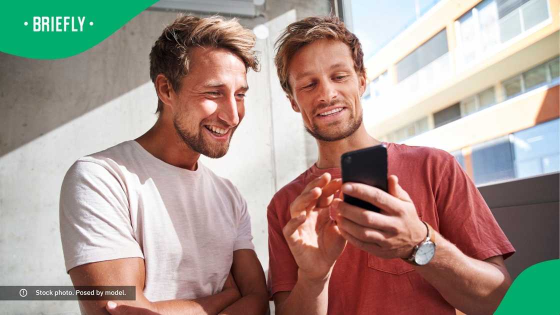 Two men laughing at a phone.