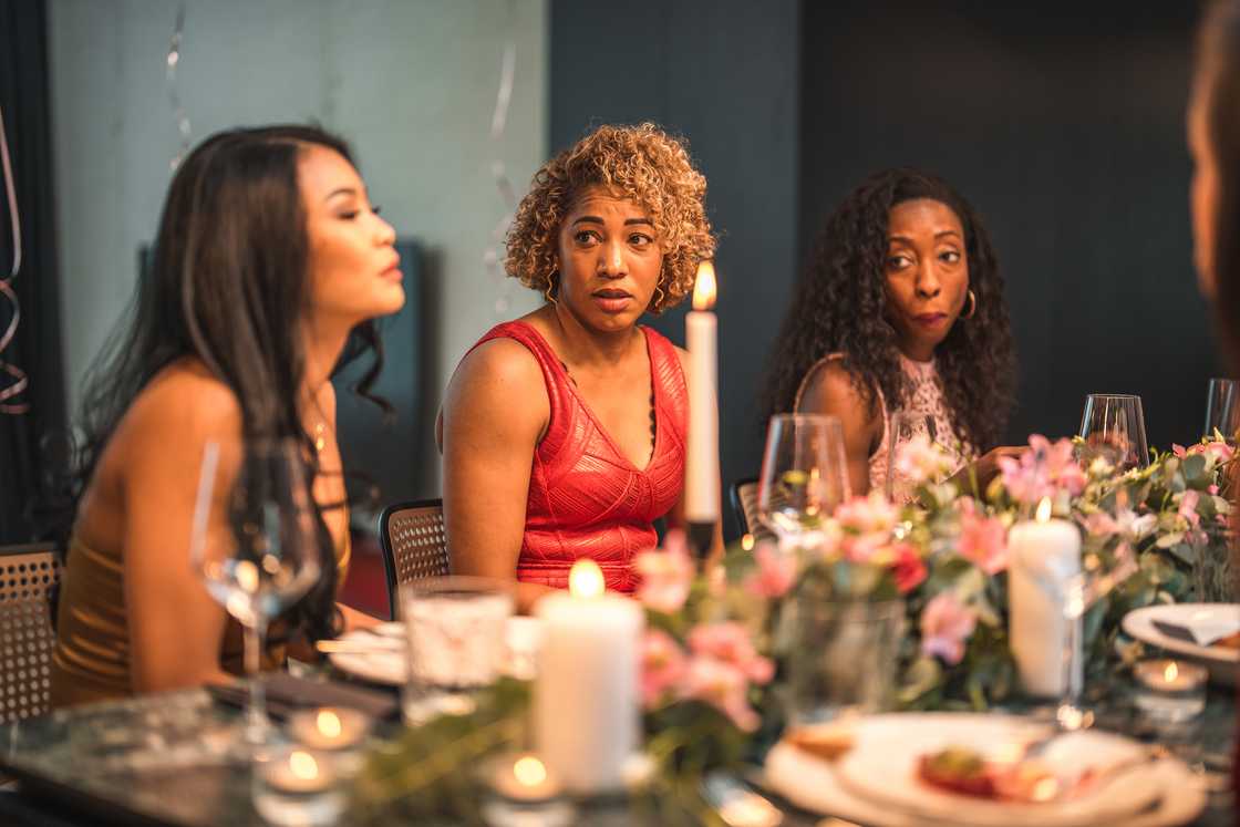 A woman shocked during a dinner table scene.