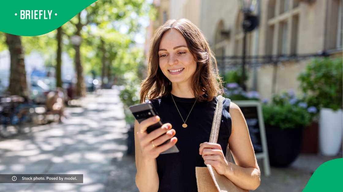 A woman smiling at her phone.
