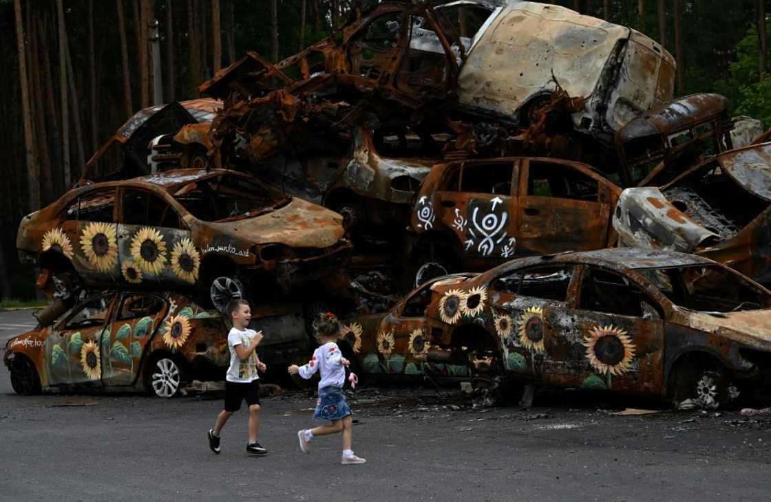 Children play near burnt-out cars -- some decorated by artists -- in Ukraine's Irpin near the capital Children play near burnt-out cars -- some decorated by artists -- in Ukraine's Irpin near the capital
