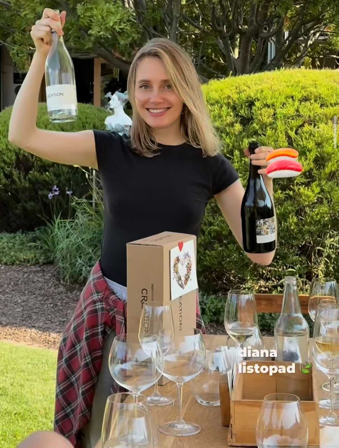 An American woman held up two wine bottles while exploring Cape Town.