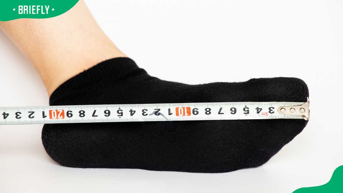 A female foot in a sock and measuring tape on a white background A female foot in a sock and measuring tape on a white background
