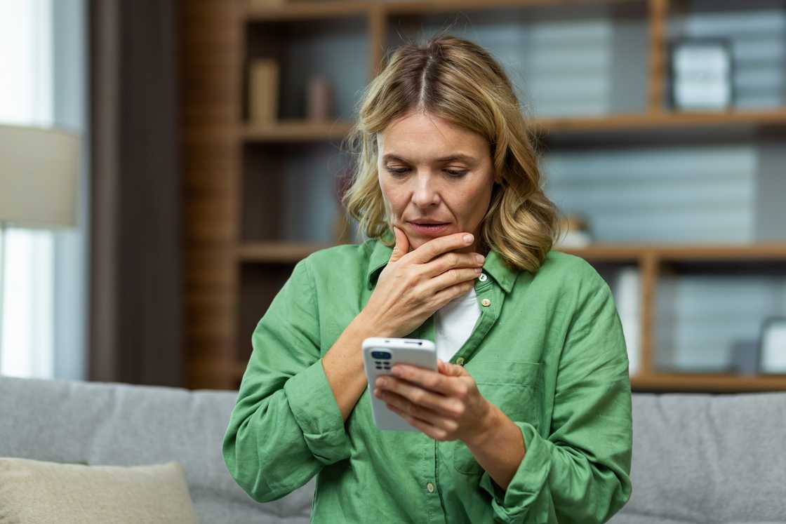 A confused woman looking at her phone.