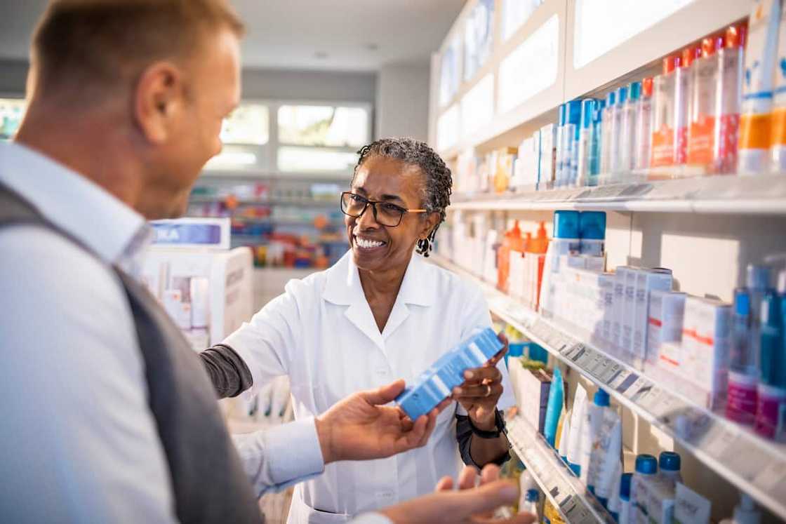 Happy chemist assisting senior customer at drugstore