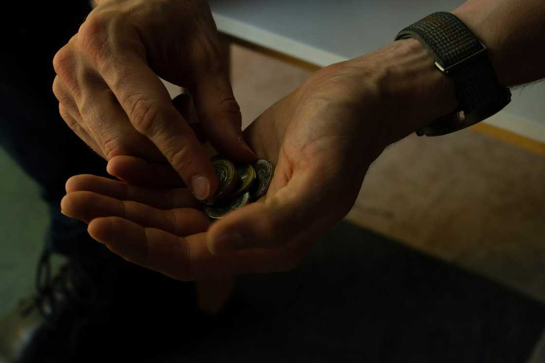 Hands counting small coins, suggesting limited money. Hands counting small coins, suggesting limited money.