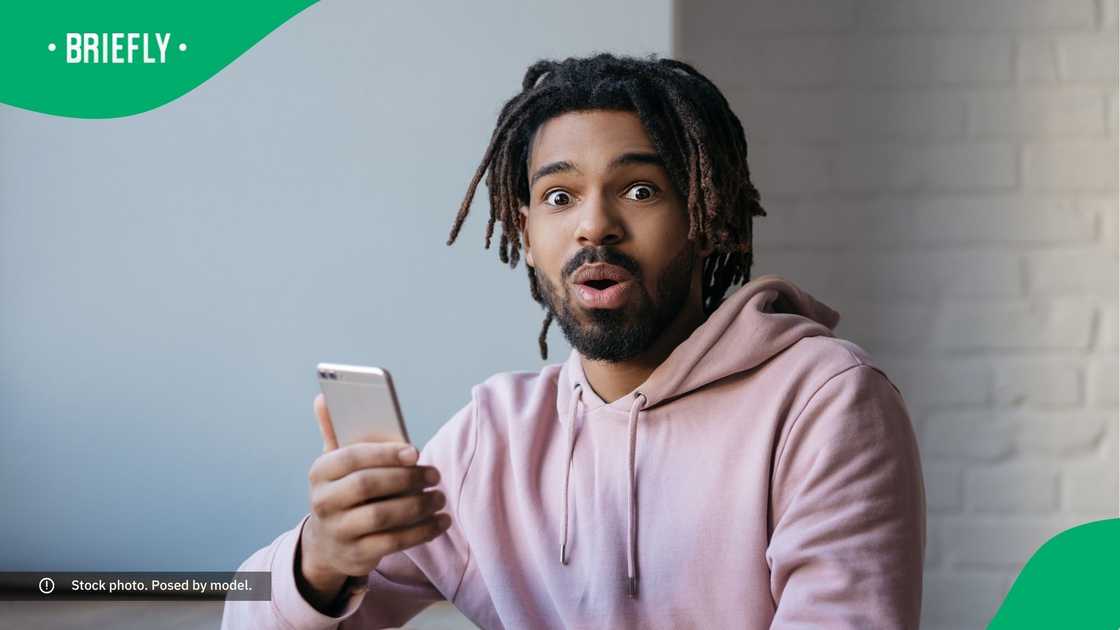 A surprised man holding a smartphone.
