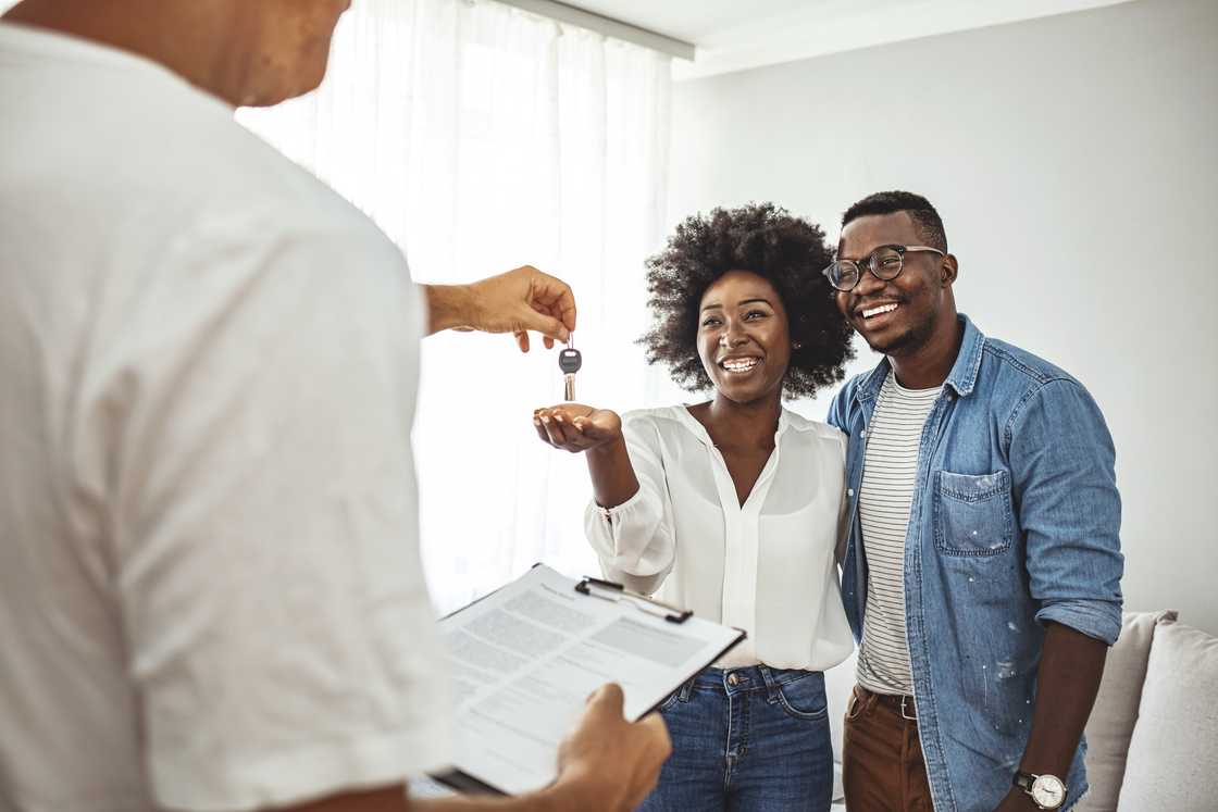 A young couple receives the keys to their new apartment from a letting agent.