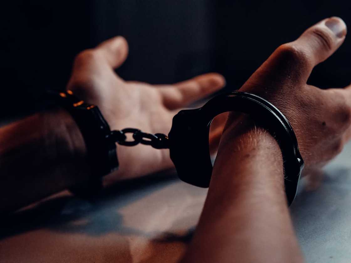 A persons hands on a the table wearing handcuffs.