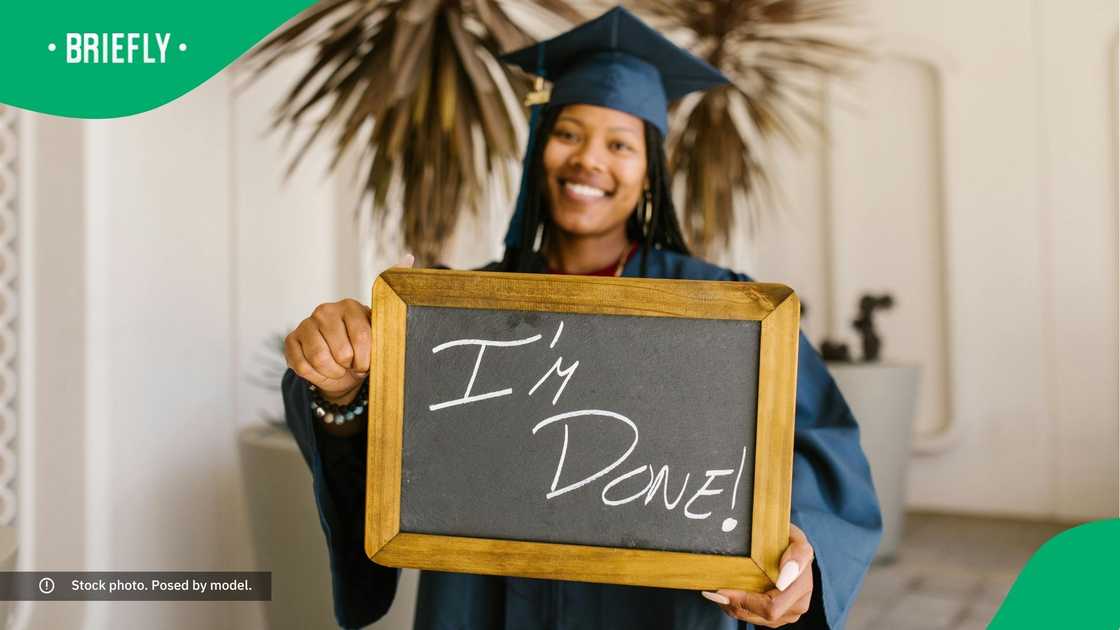 A graduate holding a small chalk board saying, "I'm done!"