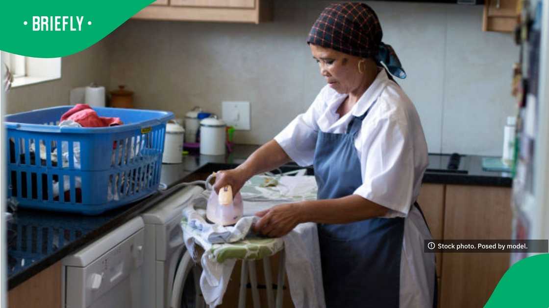 The stock photograph captured a woman doing household laundry chores next to a full blue plastic basket and a washing machine The stock photograph captured a woman doing household laundry chores next to a full blue plastic basket and a washing machine