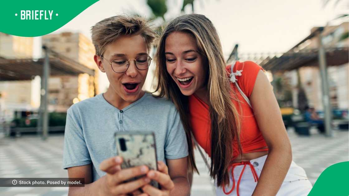 Teenagers smiling at a phone. Teenagers smiling at a phone.
