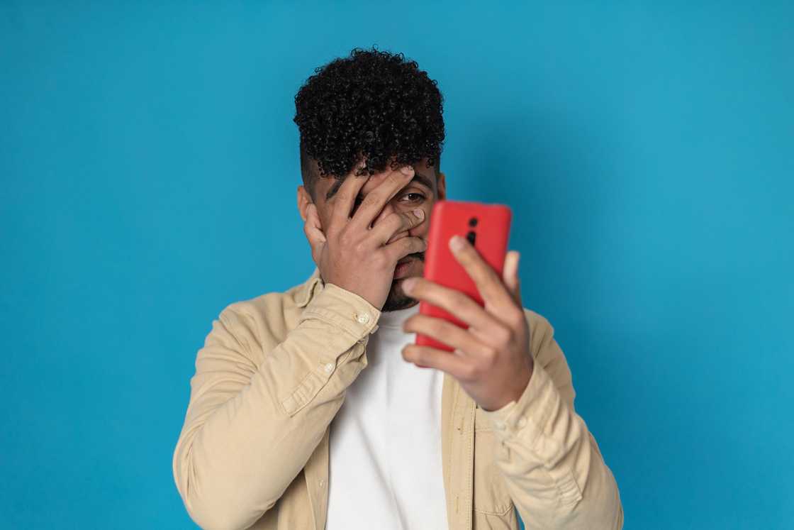 A scared man trying not to look at his phone. A scared man trying not to look at his phone.
