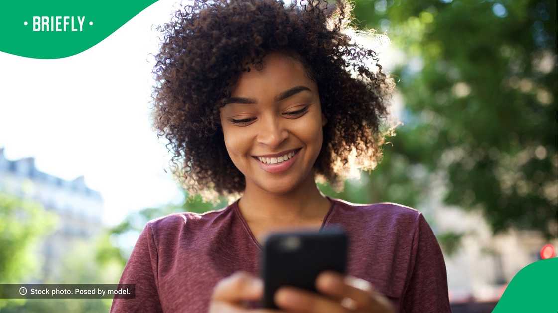A woman smiling at her phone.
