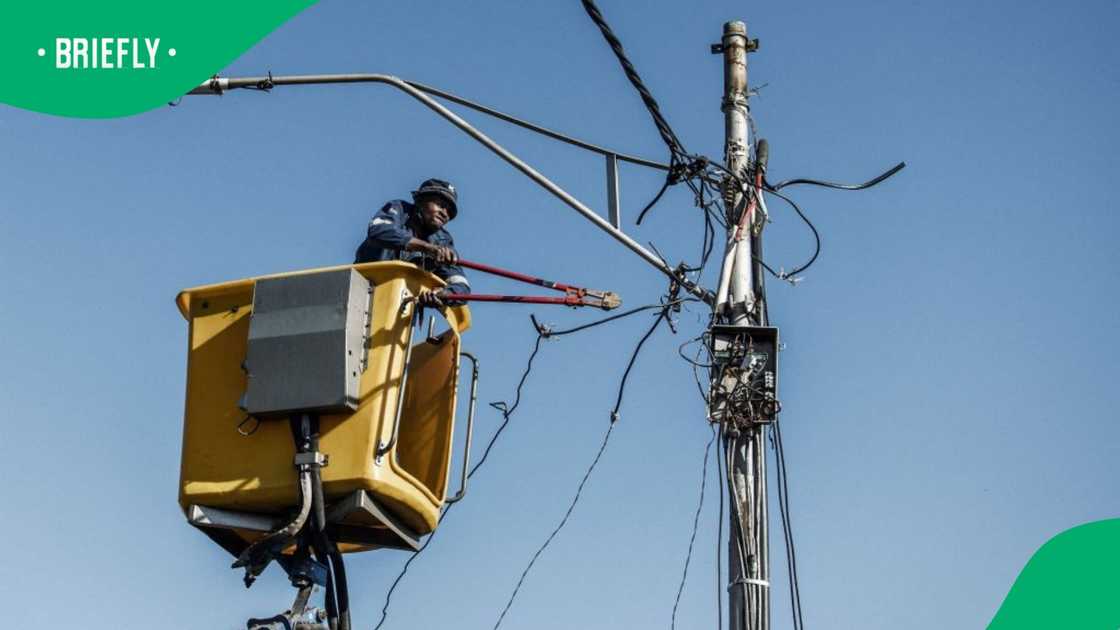 A City Power worker uses wire cutter to cut and remove an illegally connected electrical cable used by residents of an informal settlement in the Brixton area of Johannesburg to connect to the electrical grid