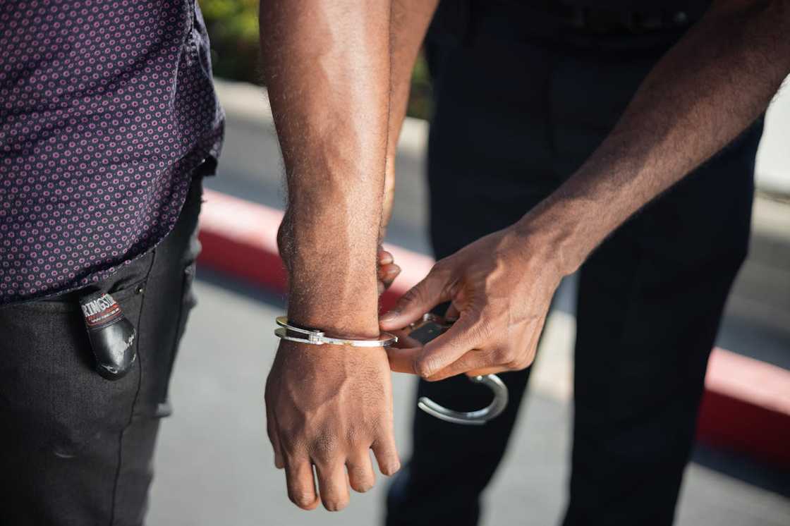 A police officer places handcuffs on a man's wrist.