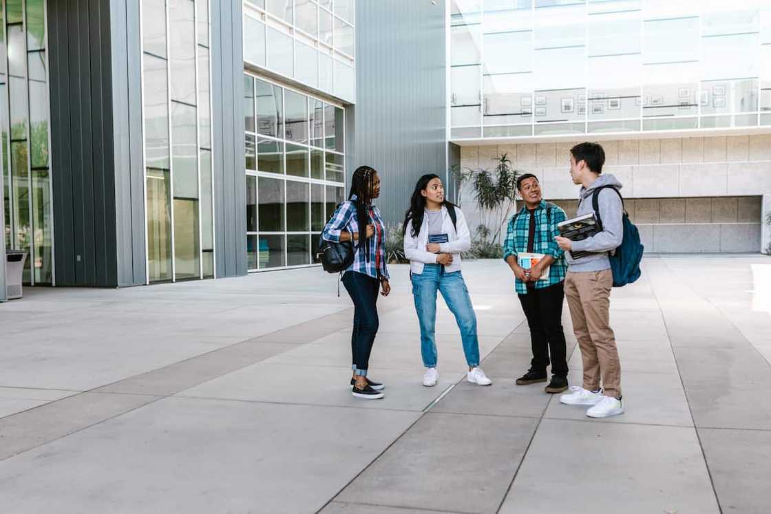 Four students talking outside a campus building.