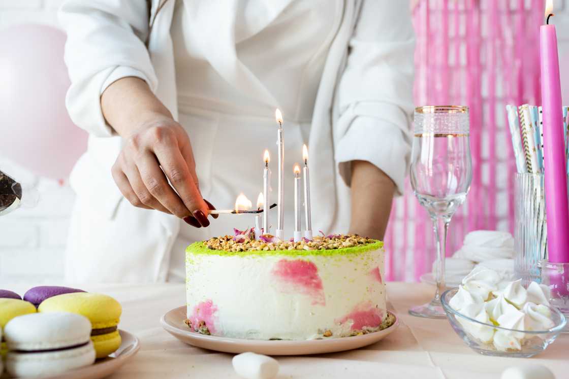 A person lights candles on a birthday cake.