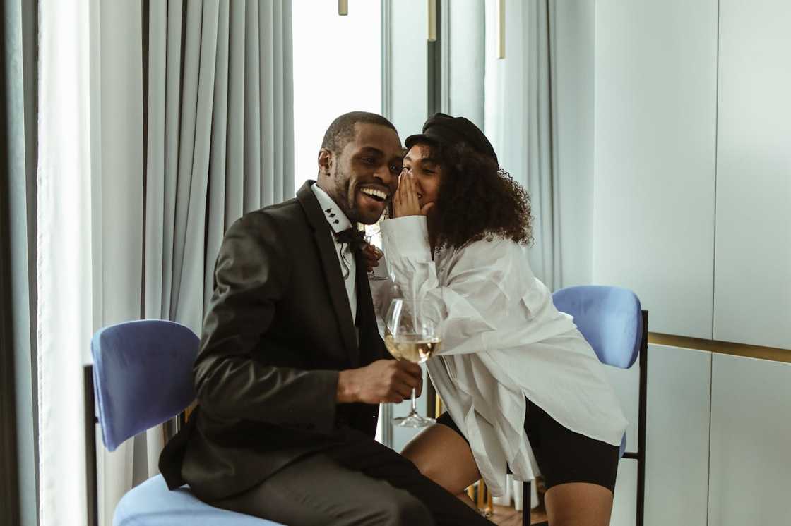 A woman whispers in the ear of a man. A woman whispers in the ear of a man.