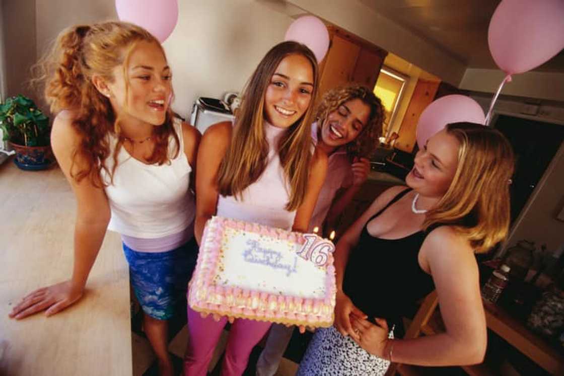 A group of teenage girls celebrating with a cake and balloons A group of teenage girls celebrating with a cake and balloons