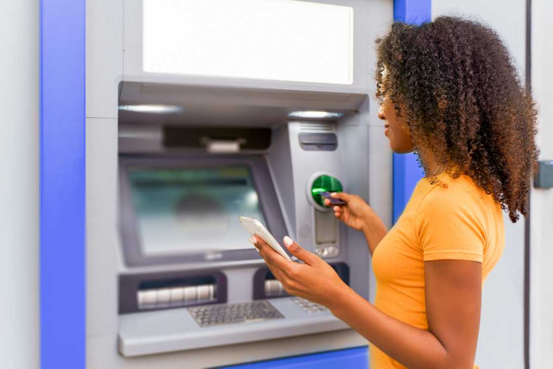 A woman standing at an ATM.