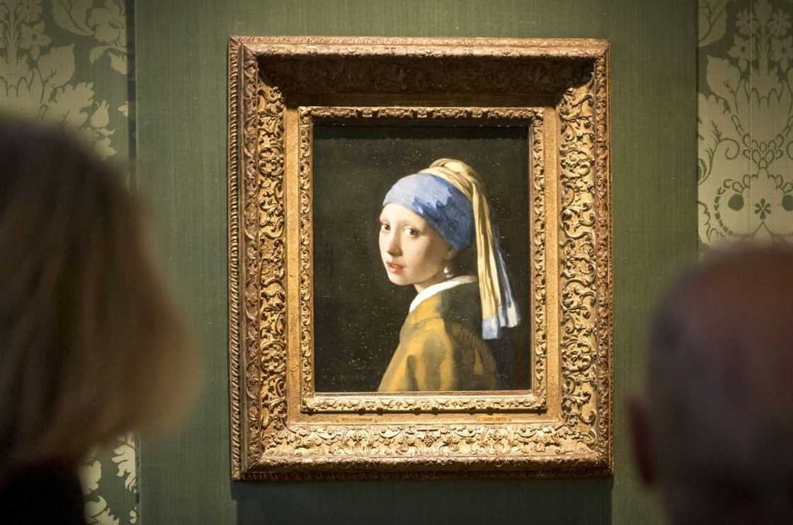 Two activists glued themselves to Johannes Vermeer's 'Girl with a Pearl Earring' and the adjoining wall, but the artwork was behind glass and undamaged Two activists glued themselves to Johannes Vermeer's 'Girl with a Pearl Earring' and the adjoining wall, but the artwork was behind glass and undamaged