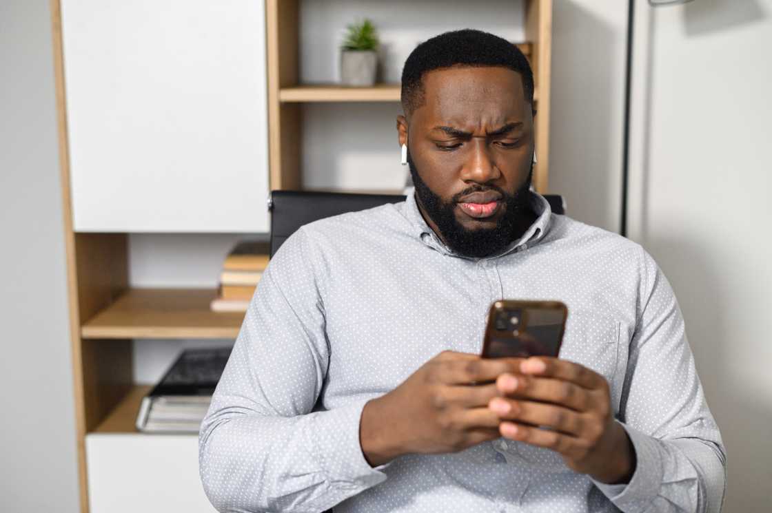 An upset man looking at his phone.