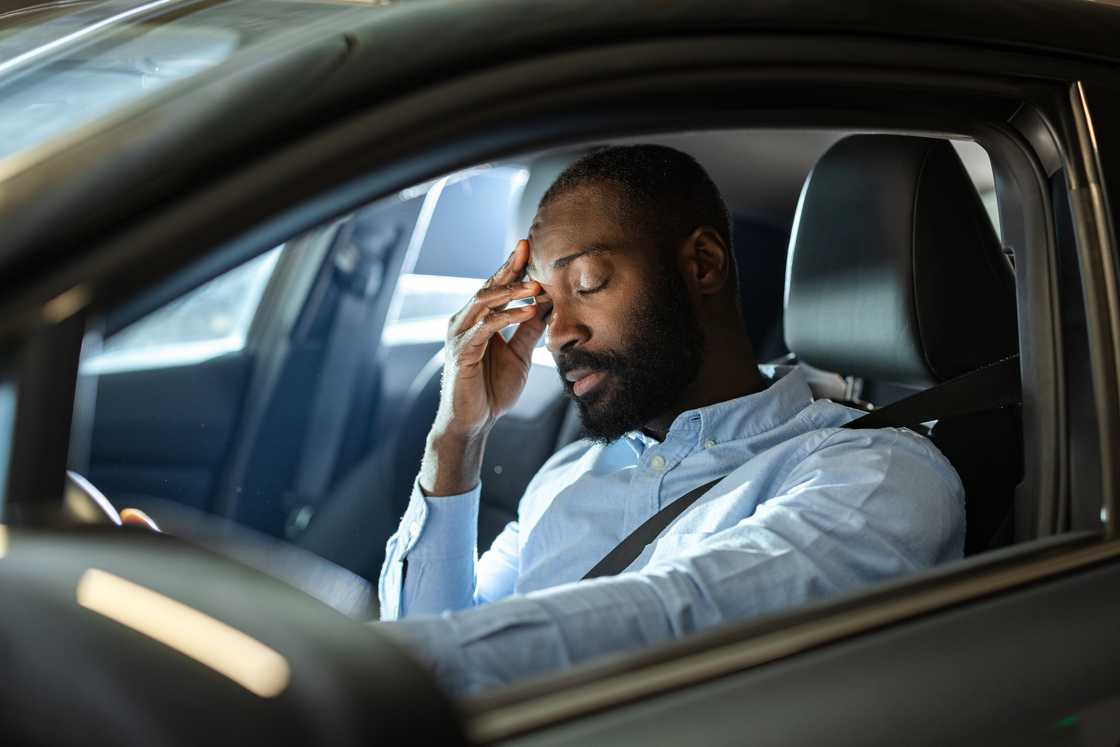 A stressed man sleeping inside his car