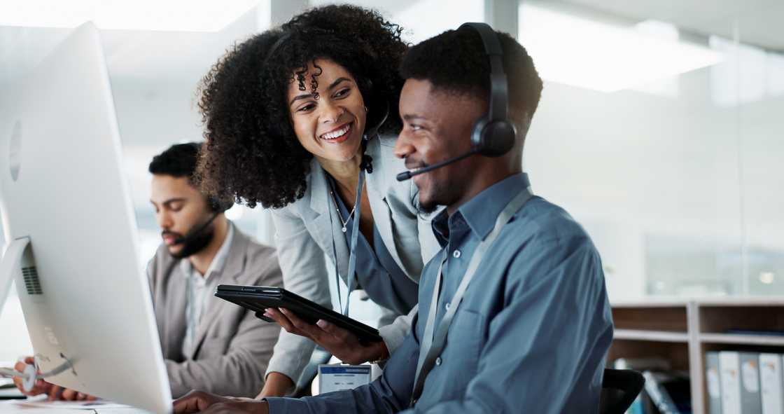 Call centre agents smile and chat between calls on the production floor. Call centre agents smile and chat between calls on the production floor.