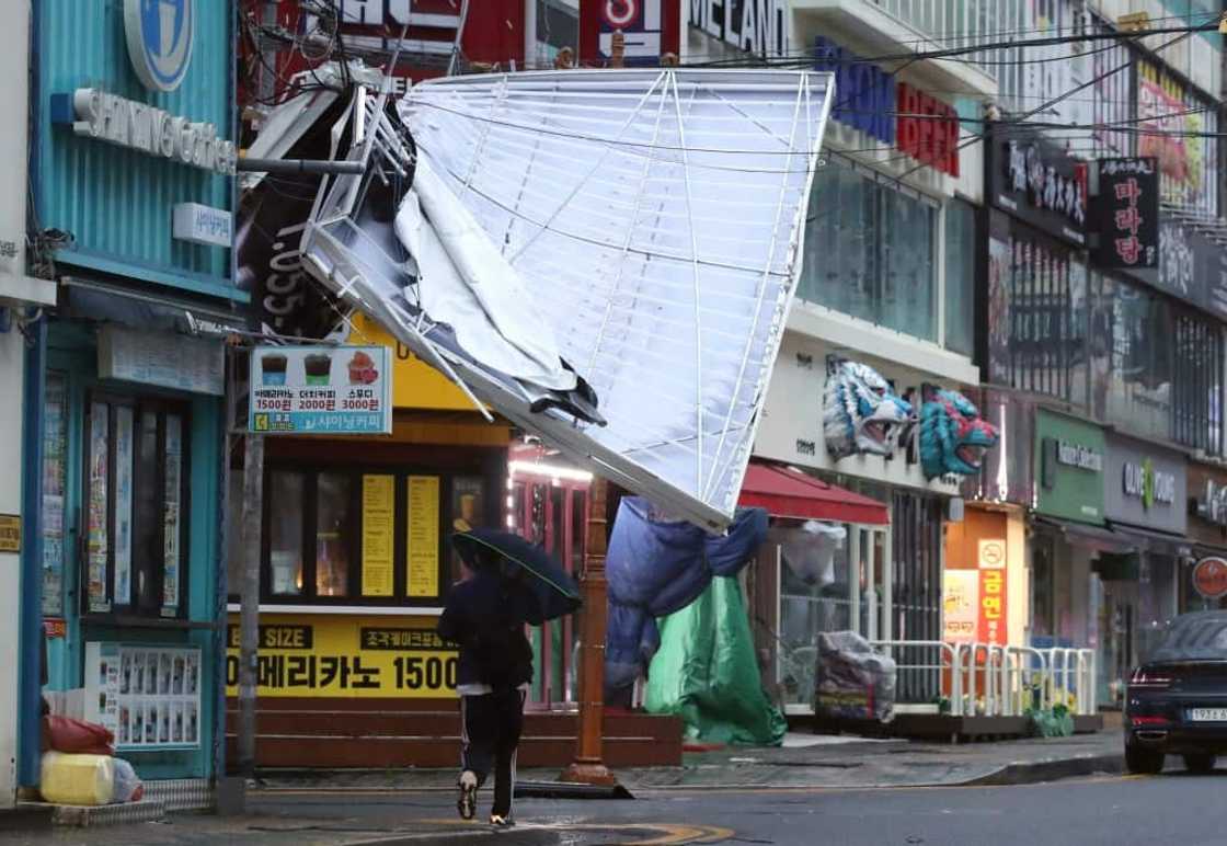 A man walks under the wreckage of a damaged signboard on a shopping street in Changwon, South Korea on Tuesday A man walks under the wreckage of a damaged signboard on a shopping street in Changwon, South Korea on Tuesday
