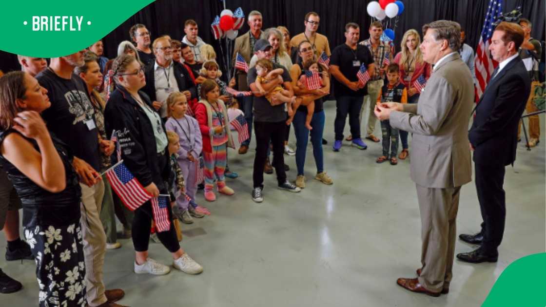 The photograph documented a gathering of families and individuals holding patriotic decorations during a political presentation The photograph documented a gathering of families and individuals holding patriotic decorations during a political presentation