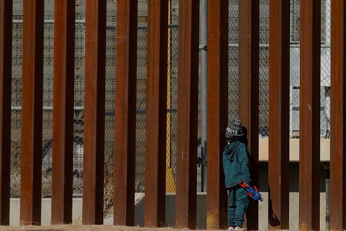 A Venezuelan child migrant stands by the wall along the Mexican-US border A Venezuelan child migrant stands by the wall along the Mexican-US border