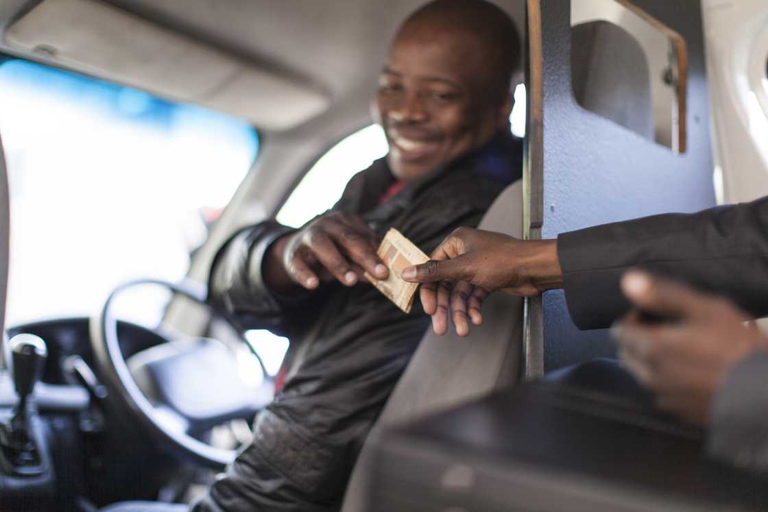 A minibus taxi driver receiving money A minibus taxi driver receiving money